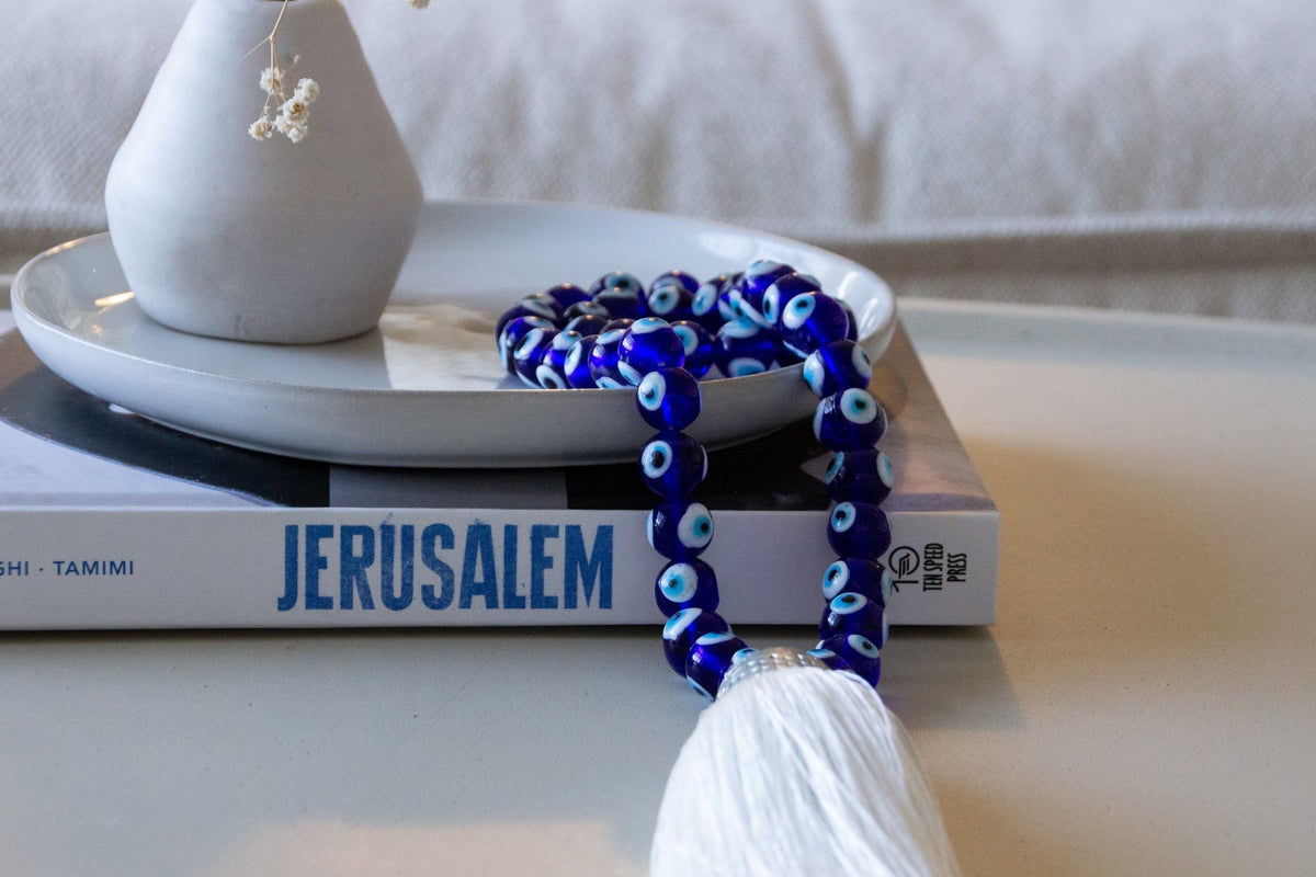 Evil eye bead strand • Blue evil eye • Glass bead evil eye • Handmade evil eye • Misbaha beads • Modern prayer beads • Table decor evil eye • Boho home decor • Evil eye protection • Mediterranean home decor • Housewarming gift • Meaningful gift • Stylish Luck • Made in Israel
שרשרת עין הרע • חרוזי עין • שרשרת חרוזי זכוכית • עין הרע לבית • קישוט שולחן • אובייקט עיצובי