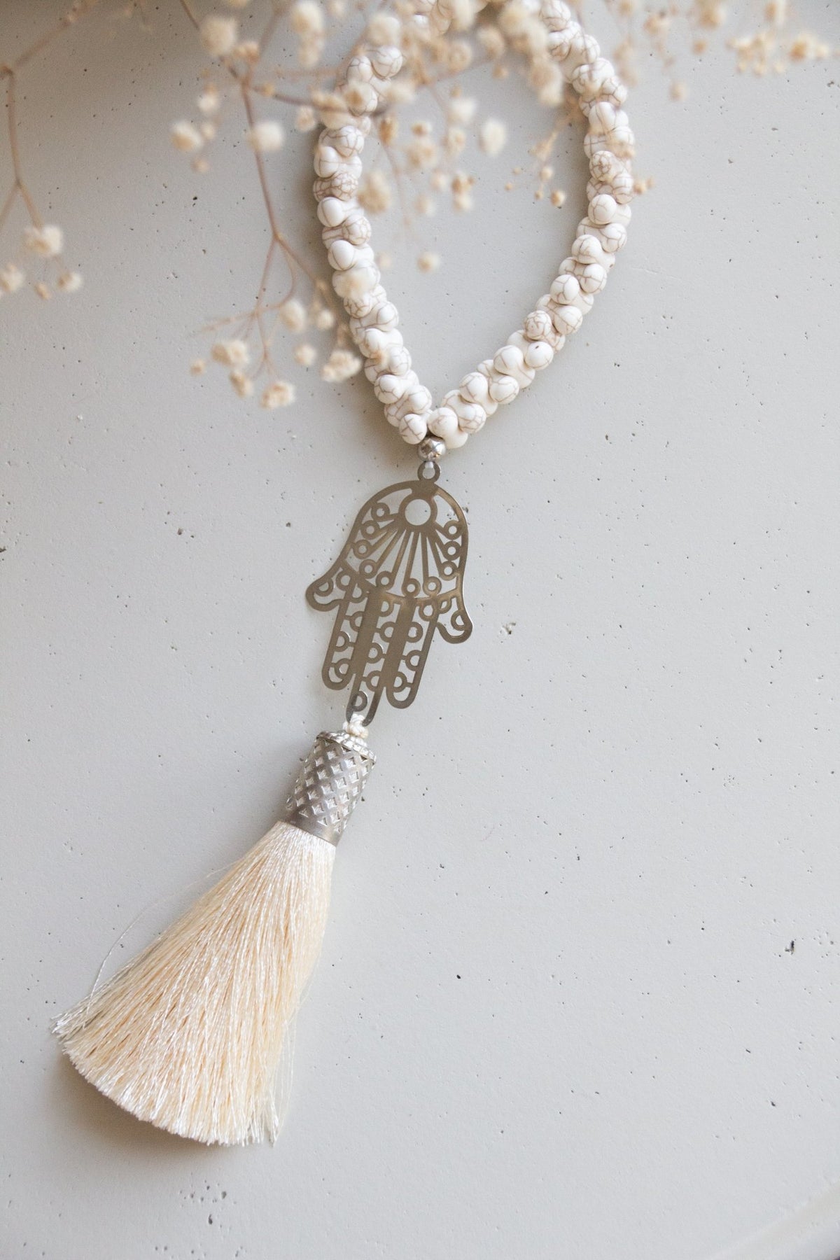 Silver-plated Hamsa hand wall hanging with cream Howlite stones and silk tassel. Modern bohemian protection charm against evil eye